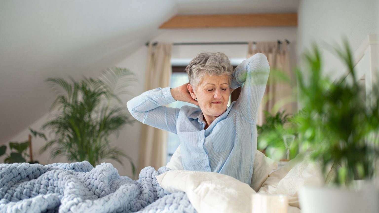 dolor de cuello al despertar Persona estirando cuello suavemente por la mañana en la cama